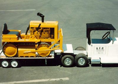 A Mack truck haulind a tractor.