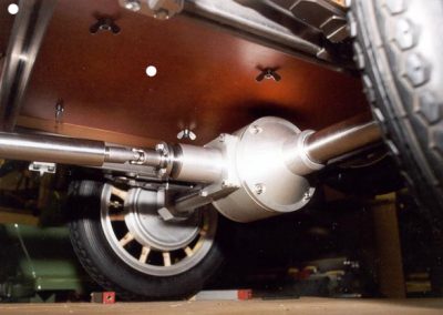 The rear axle assembly is attached to the car, and wheels are in place.