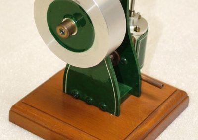 A vertical steam engine with coin for reference.