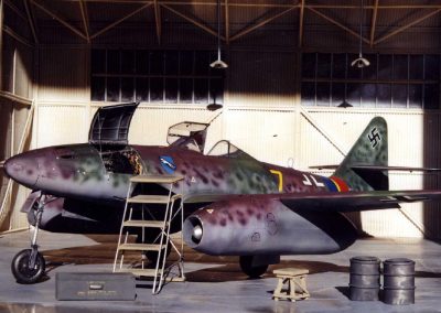 The fighter jet sits in a hangar setting.