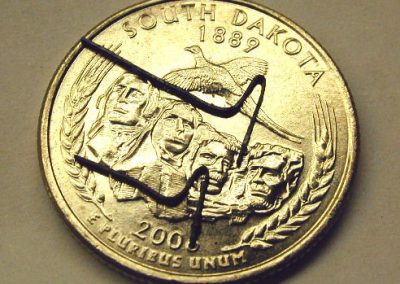 Shotgun pins sitting on a quarter.