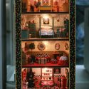 This small wall clock has had the pendulum replaced by four miniature rooms, one above the other.
