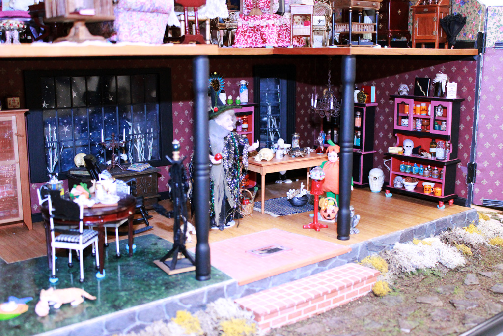 This 1/12 scale 2-story dollhouse is called, “Witch’s House.” A few miniature trick-or-treaters can be seen daring to approach the wrinkled witch.