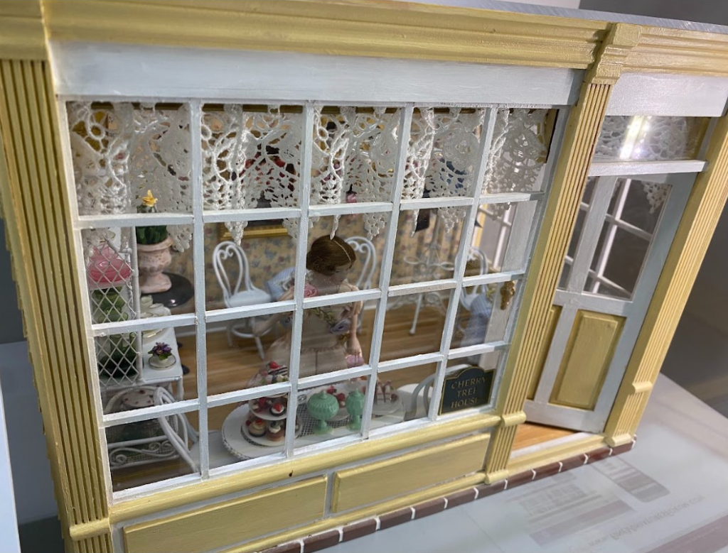 This small dollhouse built by Anita Kirwan is called the Cherry Tree House. The tiny shop is filled with delicious desserts.