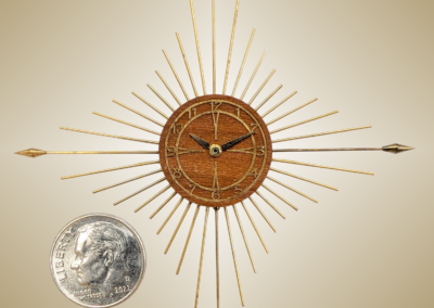 Pin Starburst Clock. Materials: Plastic movement case, walnut dial, brass numbers ring and spikes. .28x2.8x.25