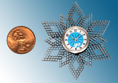 Stainless Starburst Clock. Materials: Plastic case (PLA), stainless steel “wings” and bezel, brass dial plate, glass. 2x2x.3